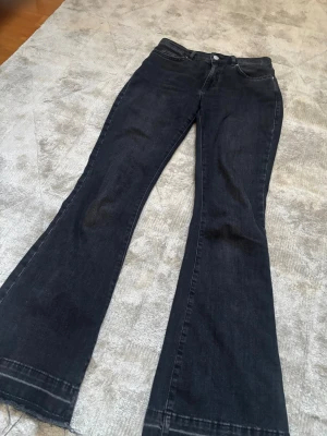 Svarta bootcut jeans med utsvängda ben -  svarta bootcut jeans som har en mörk tvätt och normal midja. 