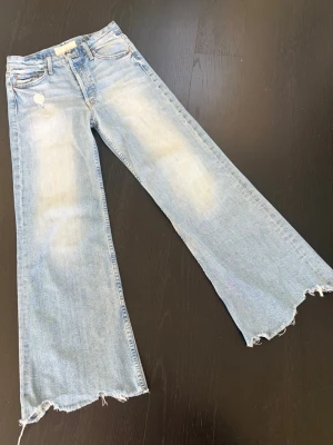 Mother  jeans med råa kanter strl.27 - Mother superior jeans med ljusa med slitningar och råa, fransiga benslut. Jeansen har klassisk femficksdesign, lätt tvättade partier och en avslappnad passform.Strl 27. 98% bomull o 2% elasthan. Perfekta för en trendig och avslappnad look. Dyra i inköp