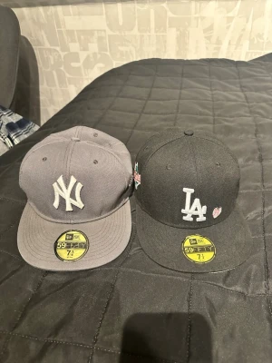 Två New Era kepsar NY & LA - Säljer två stilrena New Era 59FIFTY kepsar, en grå med New York Yankees-logga och en svart med Los Angeles Dodgers-logga och broderat hjärta. Klassisk flat peak och broderade detaljer. Den svarta är helt ny dock utan kvitto, använd typ en gång, den grå är lite mer använd. Lägg ett bud och så utgår vi därfirån, schysst pris vid snabb affär😊