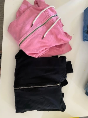 Rosa hoodie och svart hoodie - Säljer en rosa hoodie med dragkedja framtill. Och en svart hoodie med luva och dragkedja. Säljer de tillsammans