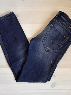 Diesel Jeans - Snygga mörkblå slim fit Jeans från Diesel med snygga slitningar. Perfekta för en avslappnad och trendig stil. Storlek W29 L32