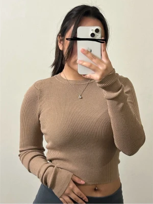 Beige ribbad tröja från Bershka - Snygg beige ribbad tröja med lång ärm och croppad passform. Rund halsringning och stretchigt material som sitter tight. 