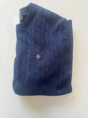 Morris merinoull kabelstickad tröja - Marinblå - En riktigt stilren kabelstickad tröja från Morris. Köpt från den officiella hemsidan. Använd fåtal gånger, så fortfarande i fint skick. Ska ej maskintvättas, gjord i merinoull. Hör gärna av dig vid frågor!😊