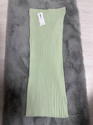 Ljusgrön ribbad långkjol Gina Tricot - Trendig ljusgrön långkjol från Gina Tricot i ribbad stickad design. Kjolen har en rak passform och är tillverkad i mjukt material som ger en bekväm känsla. Perfekt att styla med en enkel topp eller hoodie.