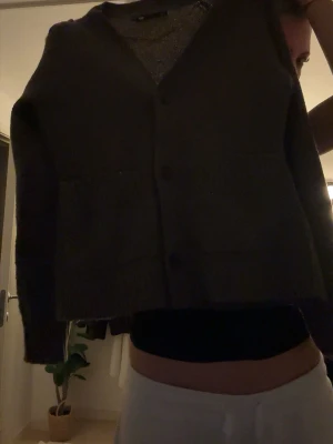 Brun kofta lager 157 - Mörkgrå stickad kofta från märket lager 157 i storlek XS. Koftan har v-ringning, knappar framtill och två stora fickor. Perfekt att slänga över en t-shirt för en chill look. Materialet är mjukt och känns skönt mot huden.