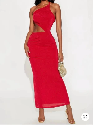 Röd oneshoulder långklänning med cut-out - Trendig röd långklänning med oneshoulder och snygg cut-out detalj i midjan. Klänningen har en figurnära passform och öppen rygg med smala band. Perfekt för dig som vill sticka ut med en modern och stilren look.