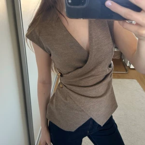 Beige/brun topp med gulddetalj - Beige/brun omlottopp med v-ringning och guldfärgad detalj i sidan. Knappt använd från Zara🩷