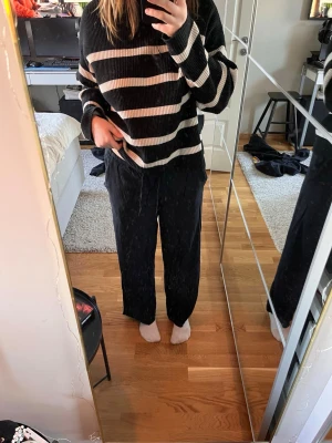 Svarta vida leggings med dragsko - Säljer ett par svarta leggings med lös passform och dragsko i midjan. De är raka i modellen och har en enkel, stilren look som passar till många outfits. Perfekta för dig som gillar bekväma och snygga byxor.