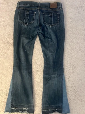 Low waist jeans - Second hand jeans som är omsydda till flare/bootcut. Ser korta ut på bilden men är ca.72 cm. Jeansen är i bra men tydligt använt skick. Lite trasiga nedtill då det en gång varit uppsydda, men ger fin detalj (se sista bild).🧡🧡🧡