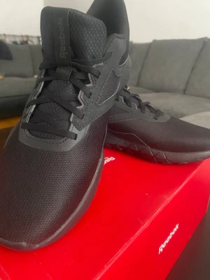 Svarta Reebok sneakers Flexagon Energy - Snygga helsvarta sneakers från Reebok, modell Flexagon Energy. Skorna har en låg siluett, ovandel i mesh och syntetmaterial för bra andningsförmåga och komfort. Klassisk Reebok-logga på sidan och tungan. Perfekta för en sportig och clean look.