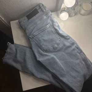 Jeans - Bikbok  - Säljer ett par ljusblå jeans med skinny fit och rå, fransad kant vid benslut. Klassisk femficksmodell med bälteshällor och knappgylf. Jeansen är i ett mjukt denimtyg och har en avslappnad vibe, perfekta till vardagslooken.