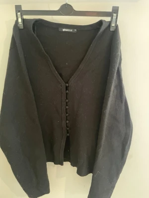 Svart kofta från Gina Tricot💗 - Svart kofta med v-ringning från Gina Tricot. Koftan har långa ärmar och knäpps framtill med små tygklädda knappar. Enkel och stilren design som passar perfekt till många olika outfits.