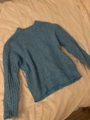 Blå ribbstickad tröja från lager 157 i stl xs  - Mysig blå stickad tröja med ribbstickat mönster och rund hals. Tröjan har långa ärmar och en avslappnad passform, perfekt för kyliga dagar. Materialet ser ut att vara mjukt och bekvämt, vilket gör den enkel att styla till olika outfits.