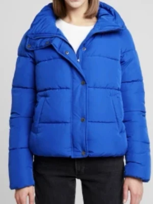 Blå pufferjacka från ONLY - Snygg blå pufferjacka från ONLY med hög krage och dragkedja samt tryckknappar framtill. Jackan har två stora fickor på sidorna och en kortare, boxig passform. Perfekt för kalla vinterdagar och ger en trendig look.