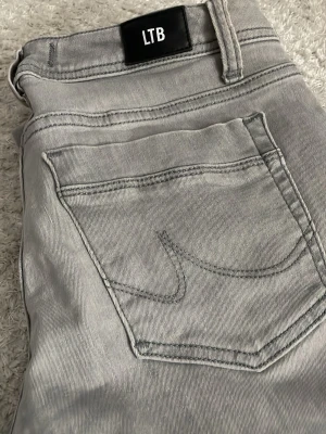 Gråa jeans från LTB - Snygga grå jeans från LTB med klassisk femficksdesign och diskreta sömmar. Jeansen har en rak passform och är tillverkade i mjukt denimtyg som ger en skön känsla. Perfekta för dig som gillar stilrena och enkla jeans.