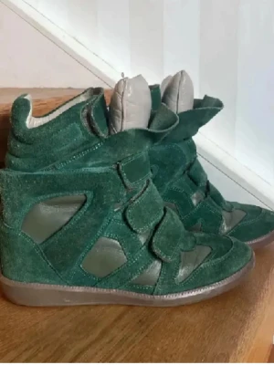 Gröna Isabel Marant wedge sneakers - Unika gröna sneakers från Isabel Marant med högt skaft och inbyggd kilklack. Skorna har en cool mix av mocka och läderdetaljer samt breda kardborreband framtill. 