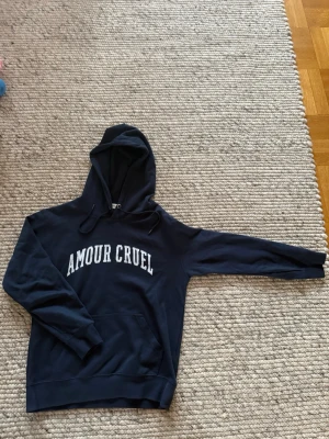 Saint Laurent hoodie - Snygg mörkblå hoodie från Saint Laurent med vit text på bröstet. Perfekt för en chill och avslappnad stil. Knappt använd så därav i toppskick. Storlek S. Hör av er vid frågor, pris är ej hugget i sten