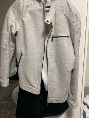 Ljusgrå bomberjacka från Zara - Snygg ljusgrå bomberjacka från Zara med dragkedjor på fickor och bröst, quiltade detaljer på axlarna och ribbade muddar. Jackan har en modern look och passar perfekt till streetwear-stilen. Köpt från Zara för 1200 för ett år sen, använd 2-3 gånger bara