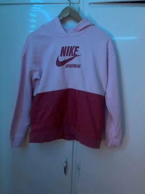 Rosa Nike hoodie med logga - Säljer en snygg hoodie från Nike i två nyanser av rosa. Stor Nike Sportswear-logga framtill. Hoodien har huva och är tillverkad i mjukt material, perfekt för en avslappnad streetstyle-look.