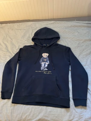 Mörkblå Ralph Lauren hoodie - Snygg mörkblå hoodie från Ralph Lauren med Polo Bear-tryck på framsidan. Står storlek M men sitter som S