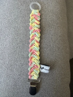 Virkad napphållare  - Virkad napphållare i pastellgrön/gul/röd. Virkad av mig i 100% bomullsgarn med metallclip och silikonring.  Mönsterskapare: animo.design