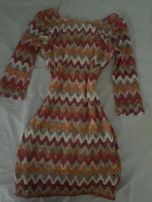 Missoni klänning från Alice by Belle Shoes - Färgglad klänning från Alice by Belle Shoes med missoni mönster i rosa, orange, beige och vitt. Klänningen har trekvartsärm och figurnära passform. Tillverkad i Italien.