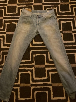 Ljusblå dondup jeans. - Säljer ett par ljusblå jeans med raka ben och diskreta slitningar framtill. Jeansen har klassisk femficksdesign och bakfickor med dekorativa sömmar. Perfekta för en avslappnad och trendig look.Skinny fit,priset är diskuterpart men kommer ej att dyka ner flera hundra lappar.