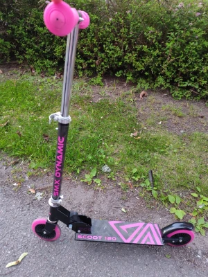 Svart och rosa sparkcykel SMX Dynamic - En svart sparkcykel med rosa detaljer från SMX Dynamic. Styret är i metall med rosa handtag och justerbar höjd. Hjul i plast med rosa kanter och fotplattan har grafiskt rosa mönster samt texten 'SCOOT 120'. Perfekt för att rulla fram snabbt och smidigt.