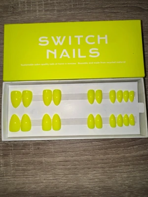 Switch Nails Electric Banana press-on - Snygga press-on naglar från Switch Nails i färgen Electric Banana. Naglarna har en kort mandelform och kommer i en starkt gul nyans. Tillverkade av återvunnet material och enkla att applicera hemma. Perfekt för dig som vill ha en färgstark look. Säljes utan tillbehör. 