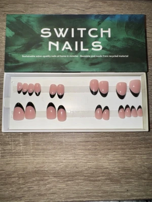 Switch Nails Black French Almond - Snygga press-on naglar från Switch Nails i modellen Black French Almond. Naglarna har en kort mandelform och är nude med svart fransk tipp. Tillverkade av återvunnet material och kan återanvändas. Perfekt för dig som vill ha trendiga naglar snabbt. Säljes utan tillbehör och det är klisterrester i ena 3:an, en 4:a, en 8:a och en 11:a.