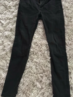 Svarta skinny jeans - Säljer ett par svarta skinny jeans med klassisk femficksdesign och dragkedja fram. Jeansen har smal passform och raka ben, perfekta till en avslappnad eller edgy stil. Materialet känns mjukt och stretchigt för extra komfort.