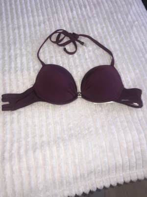 Mörklila push-up bh med halterneck - Snygg mörklila push-up bh från newyorker med halterneckband och vadderade kupor. Bh:n har en metallspänne framtill och diskret logga på sidan. Perfekt för dig som vill ha extra stöd och lyft. 