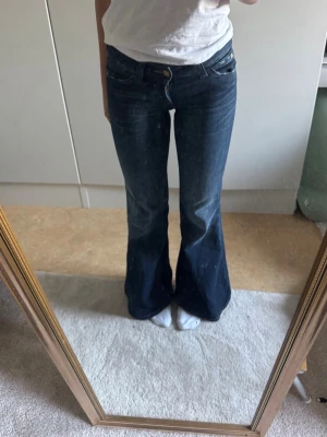 Mörkblå bootcut/flare jeans - Snygga mörkblå bootcut jeans med klassisk femficksmodell och låg midja. Jeansen har en  utsvängd passform nertill. Perfekta för dig som gillar en retrostil eller trendigstil!