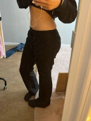 Svarta kostymbyxor med raka ben - Snygga svarta kostymbyxor med raka ben och låg midja. Byxorna har pressveck framtill och sidfickor. Perfekta för en clean och stilren look. Materialet ser ut att vara en mjuk och följsam polyesterblandning.