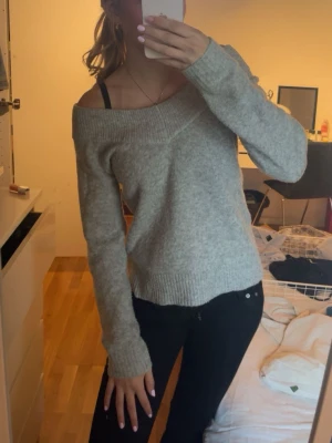  stickad tröja - Mysig ljusgrå stickad tröja med off shoulder-modell och långa ärmar. Tröjan har ribbstickade muddar vid ärmslut och nederkant. Perfekt för lager-på-lager och chill stil, passar till både jeans och kjol.