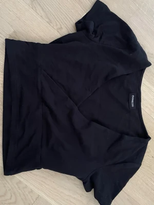 Svart omlottopp från Even&Odd - Svart omlottopp från Even&Odd med kort ärm och v-ringad hals. Toppens material känns mjukt och stretchigt, perfekt för en trendig och enkel look. Passformen är normal och toppen är lätt att matcha med olika outfits.