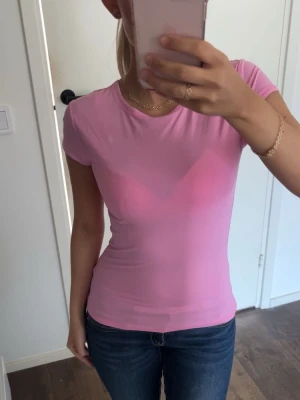 Rosa tight t-shirt  - Säljer en ljusrosa, tight t-shirt med korta ärmar och rund halsringning. T-shirten är enkel och stilren, perfekt att matcha med jeans eller kjol. Materialet känns mjukt och stretchigt.