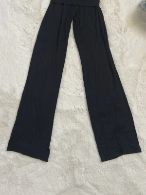 Svarta vida leggings från Aware - Säljer ett par svarta leggings från Aware i storlek XS. De har en mellan låg midja och vida ben, vilket ger en avslappnad och trendig look. Perfekta att styla med en oversized hoodie eller crop top. Materialet är mjukt och stretchigt för extra komfort.