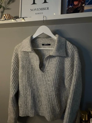 Grå stickad tröja från Gina Tricot - Mysig grå stickad tröja från Gina Tricot med v-ringning och krage. Sticks inte. Inte använd 