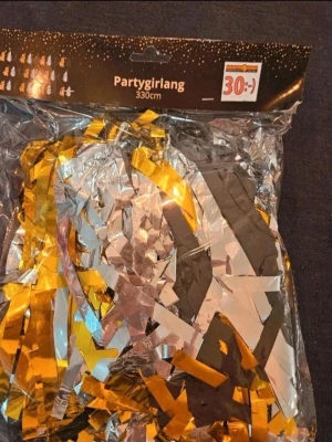 Partygirlang 330 cm guld och silver - En festlig partygirlang på 330 cm i glansigt guld och silver. Perfekt för att dekorera till kalas, nyår eller andra firanden. Tillverkad av tunn plastfolie som reflekterar ljuset snyggt och ger extra partykänsla.