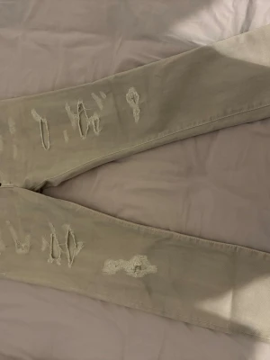 Beige slitna jeans från Dsquared2 - Snygga beige jeans från Dsquared2 med slitna detaljer och hål på benen. Modellen har klassisk femficksdesign och raka ben. Perfekta för en trendig och avslappnad stil. Materialet är bomull med en mjuk känsla.