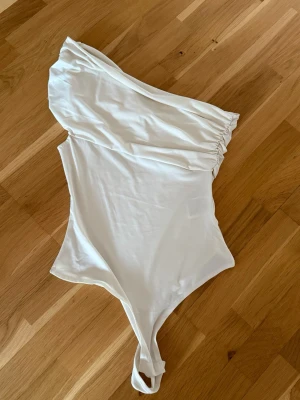 Vit body - Snygg one-shoulder body från HM. Använd 1gång så väldigt fint skick💕