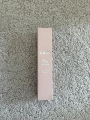 Oöppnad CAIA All Eyes On Me Primer - CAIA All Eyes On Me är en ögonskuggsprimer i en stilren, ljusrosa förpackning. Produkten hjälper till att få ögonskuggan att sitta längre och intensifierar färgerna. Förpackningen är av kartong och har en smal, rektangulär form med vit text. Nypris: 245kr!