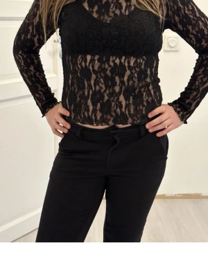 Svart spetsblus från Kappahl - Snygg svart långärmad blus från Kappahl i genombruten spets. Blusen har rund halsringning och är perfekt för dig som gillar en elegant och trendig look. Materialet är lätt och luftigt, vilket gör den skön att bära.