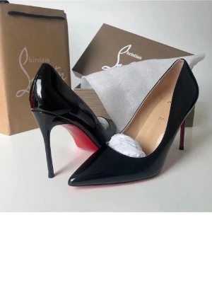 Svarta lackpumps från Louboutin - Säljer ett par klassiska svarta pumps i glansigt lack från Christian Louboutin. Skorna har spetsig tå, hög smal klack och den ikoniska röda sulan. Perfekta för dig som vill ha en elegant och tidlös look.