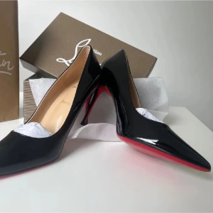 Svarta lackpumps från Louboutin - Snygga svarta pumps i lack från Christian Louboutin med klassisk spetsig tå och ikonisk röd sula. Skorna har hög klack och elegant form, perfekta för att lyfta vilken outfit som helst. Materialet är glansigt läder som ger en lyxig känsla.
