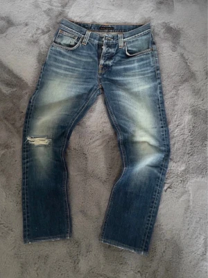 Nudie Jeans Grim Tim - Tja! Säljer ett par sjukt snygga vintage Nudie Jeans. Väldigt snygg tvätt och snygga detaljer. Modell Grim Tim - SlimStraight, Storlek - W32 L32, men skulle säga att de sitter L30. Pris ej hugget i sten.