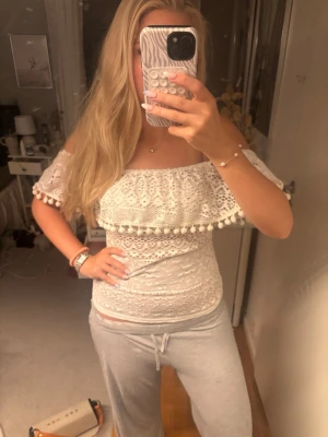 Vit offshoulder topp - Säljer en vit offshoulder blus med spetsmönster och volang med små bollar längs kanten. Hör av er om ni har några frågor!!💕