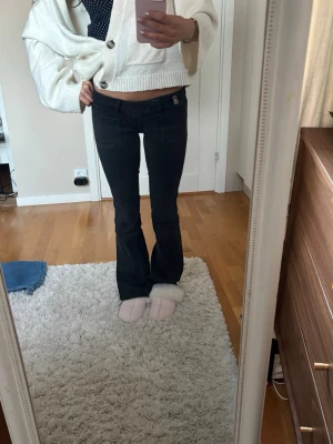 Lågmidjade svarta bootcut jeans med broderi - Säljer ett par svarta bootcut jeans med snygga broderade detaljer på bakfickorna. Jeansen har låg midja och tyget är töjbart. 💕