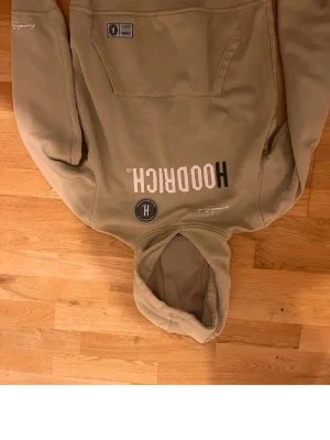 Beige hoodie från Hoodrich - Snygg beige hoodie från Hoodrich med stor magficka och tryck både fram och bak. Hoodien har en klassisk huva och ribbade muddar vid ärmslut och nederkant. Perfekt för en avslappnad streetwear-look. Materialet känns mjukt och bekvämt. Passar perfekt dig som är 164-170, Priset går att diskuteras!!